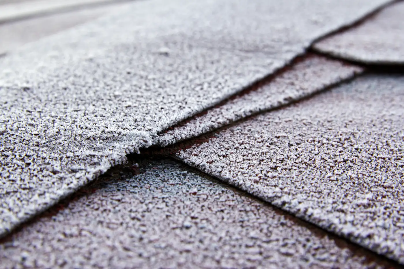 Close-up of frost on overlapping asphalt roof shingles
